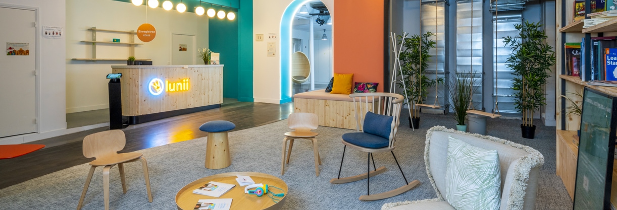 Espace collaboratif en entreprise avec un coin salon, un espace bar et du mobilier informel coloré