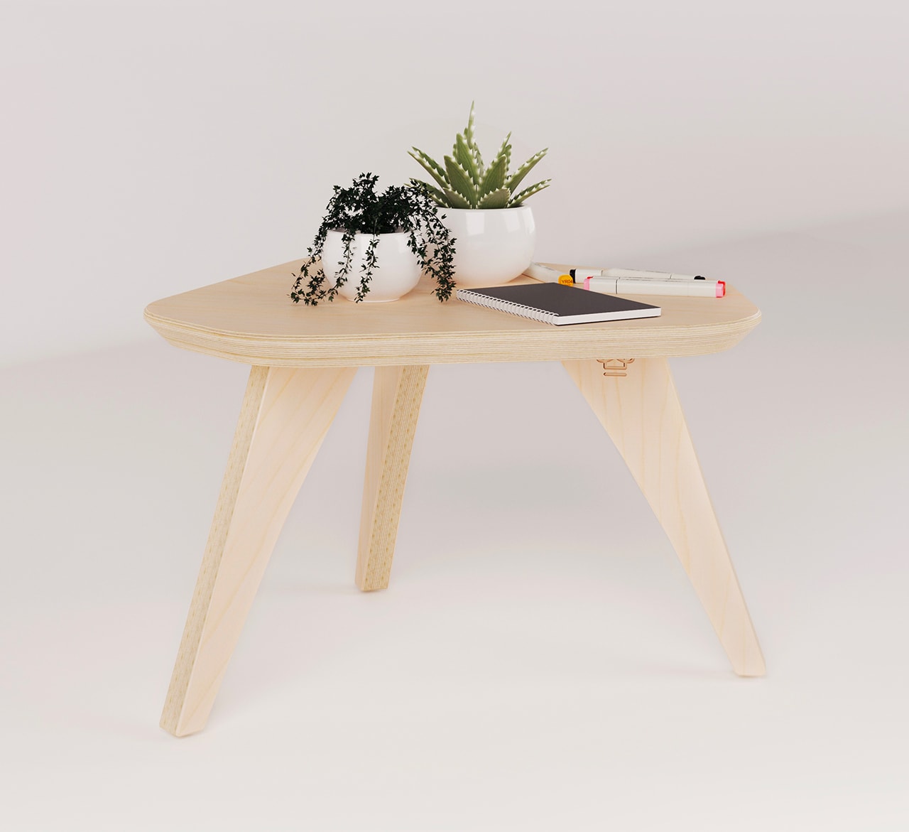 table basse 3 pieds en bois avec un carnet de note et deux plantes posées dessus