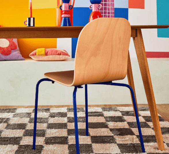 Chaise de bureau en bois avec un piétement bleu foncé ainsi qu'un bureau en bois et une décoration très colorée