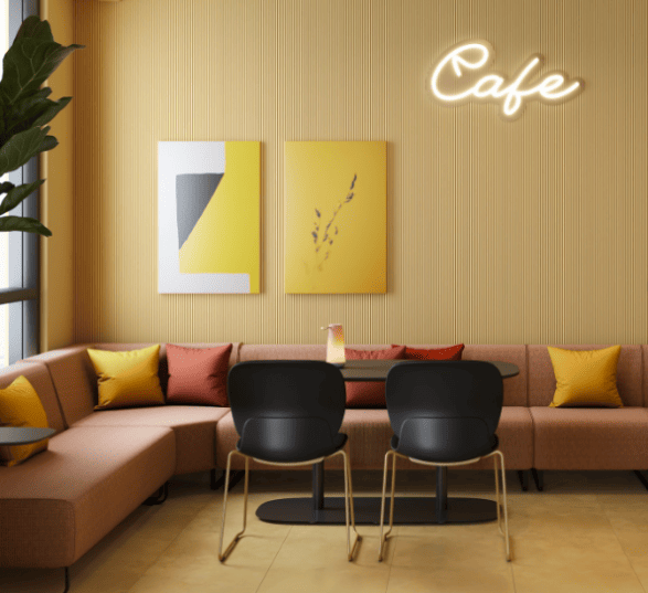 Espace informel en entreprise avec un canapé d'angle rose, une table, 2 chaises noires et des décorations murales.