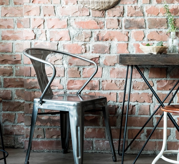 Chaise et table en métal chromé et bois avec un mur en pierres