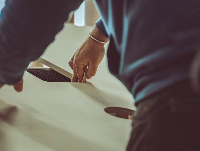 Un ébéniste ponce l'intérieur d'un plateau de table en bois