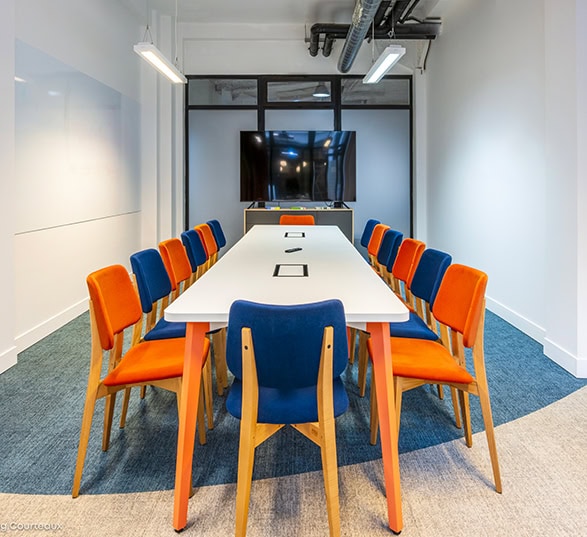 Table de réunion avec un plateau blanc et des chaises colorées