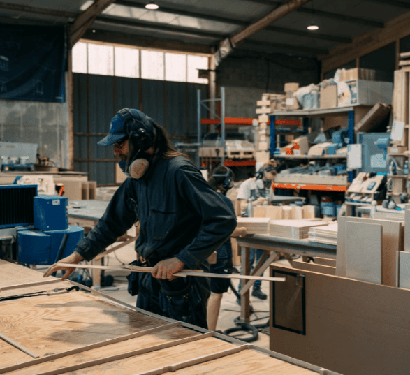 un opérateur cnc place des plaques de bois sur la machine pour usiner un meuble de bureau